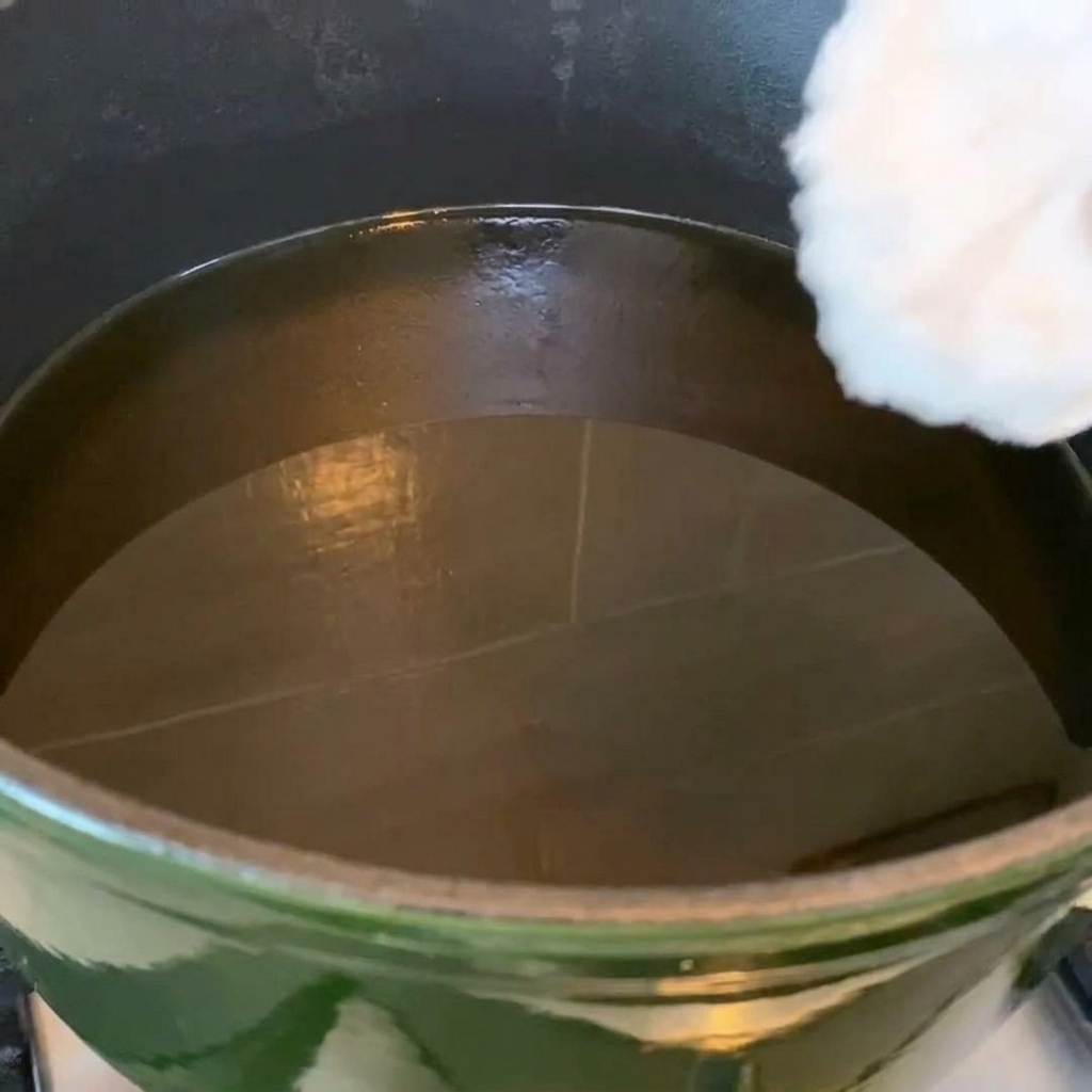 Chicken wings frying in a pan of hot oil, showing golden color.
