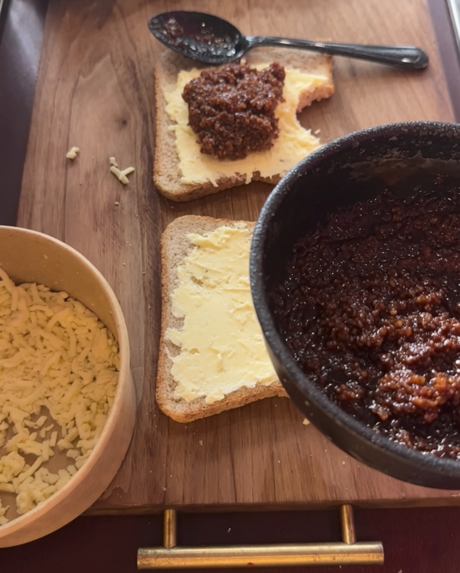 A generous portion of savory meat sauce spread over the cheese layer on the bread.