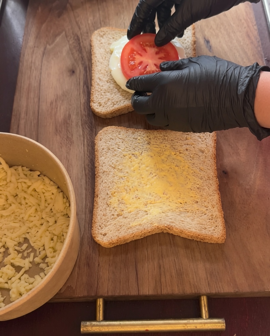 A fried sunny-side-up egg being placed on top of the meat sauce layer.