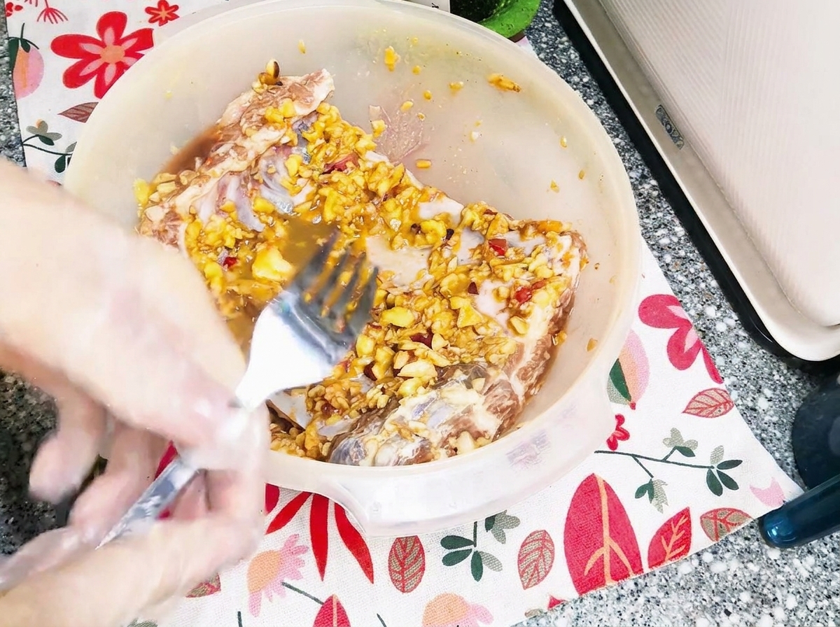 A metal fork piercing the surface of raw, marinated pork ribs in a bowl.