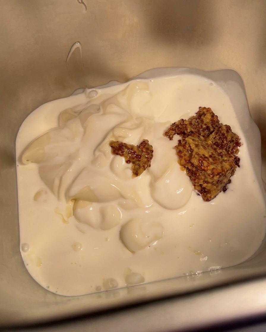 Finely chopped white onions being sprinkled into the metal container with the sauce mixture.