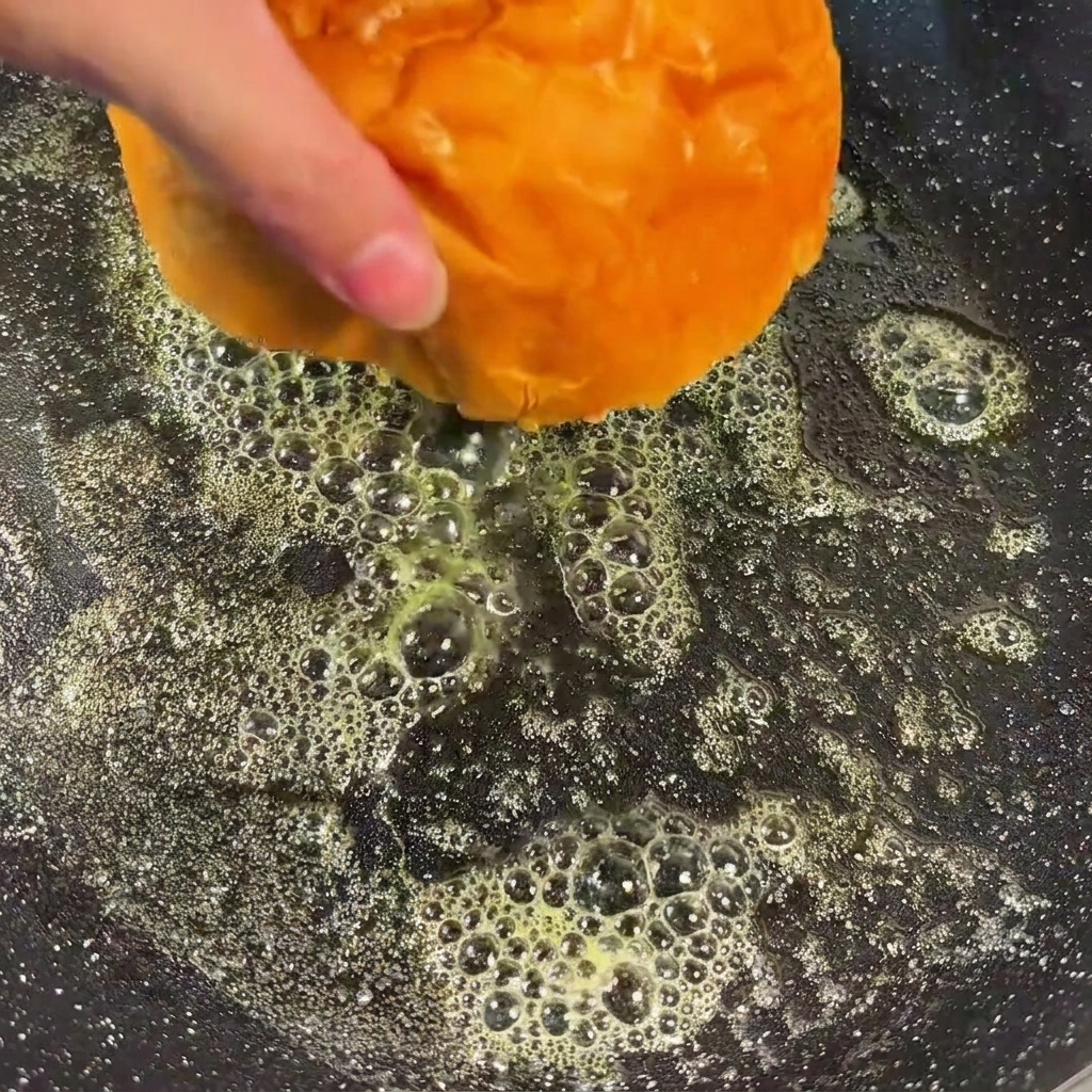 Burger bun halves face down in a pan of melted butter, toasting to a golden brown.