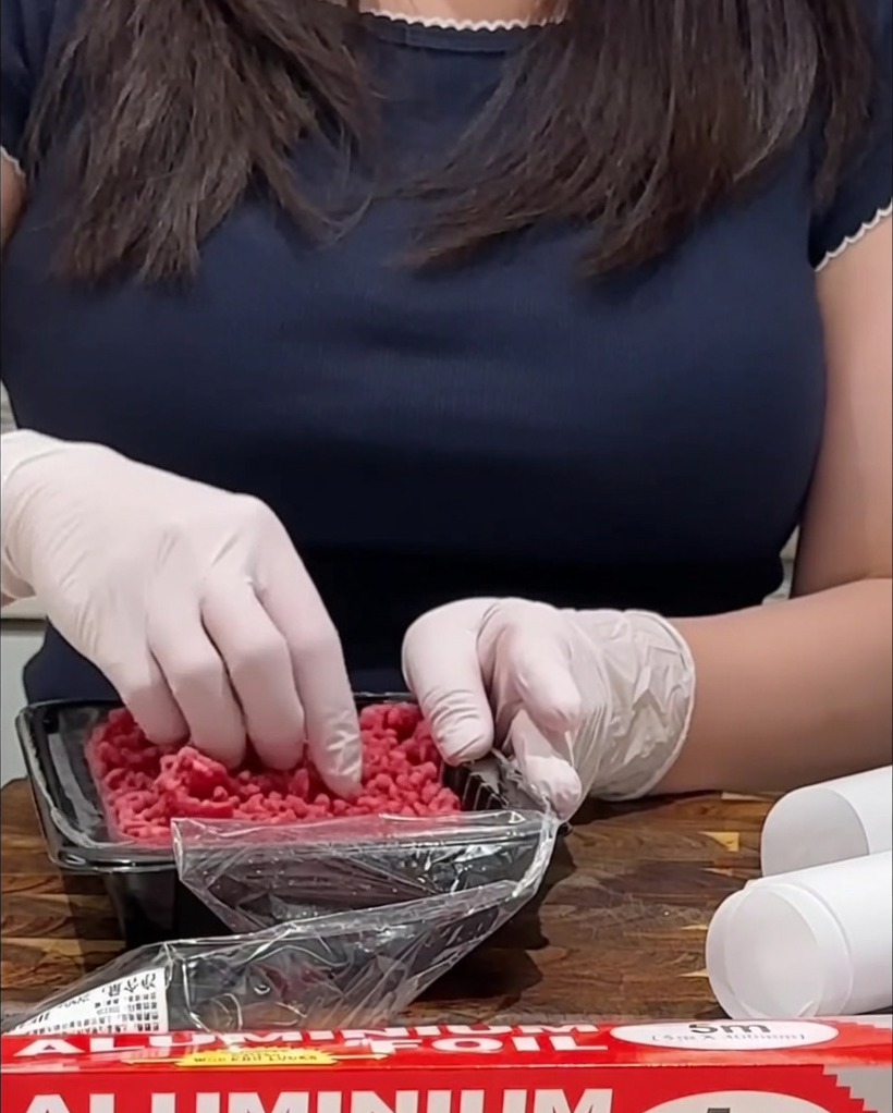 Seasoning raw ground beef patties on a wooden cutting board with salt and pepper.