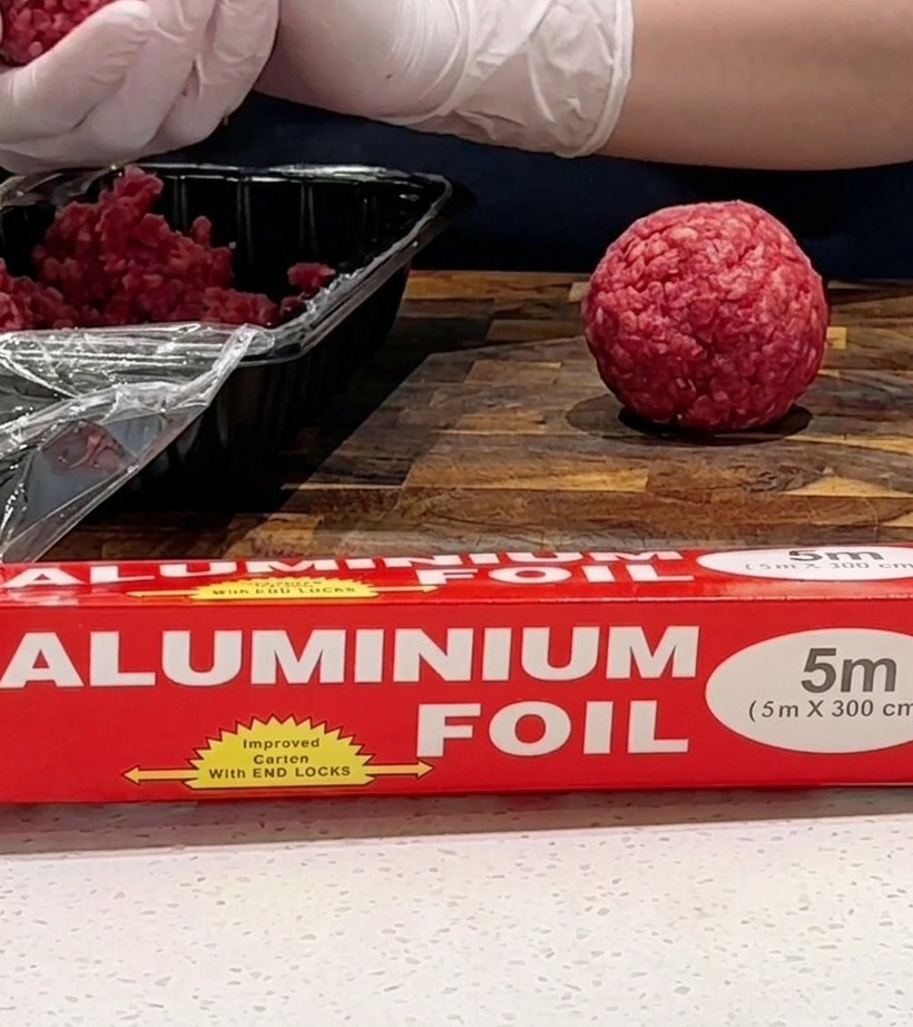 Beef patty cooking in a hot pan, developing a browned crust.