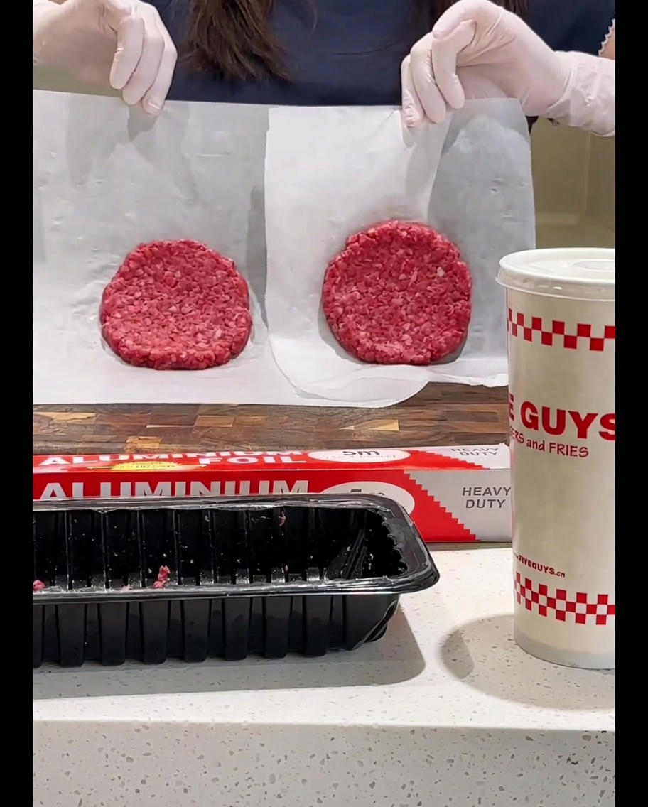 Turning the beef patty in the frying pan with a spatula.
