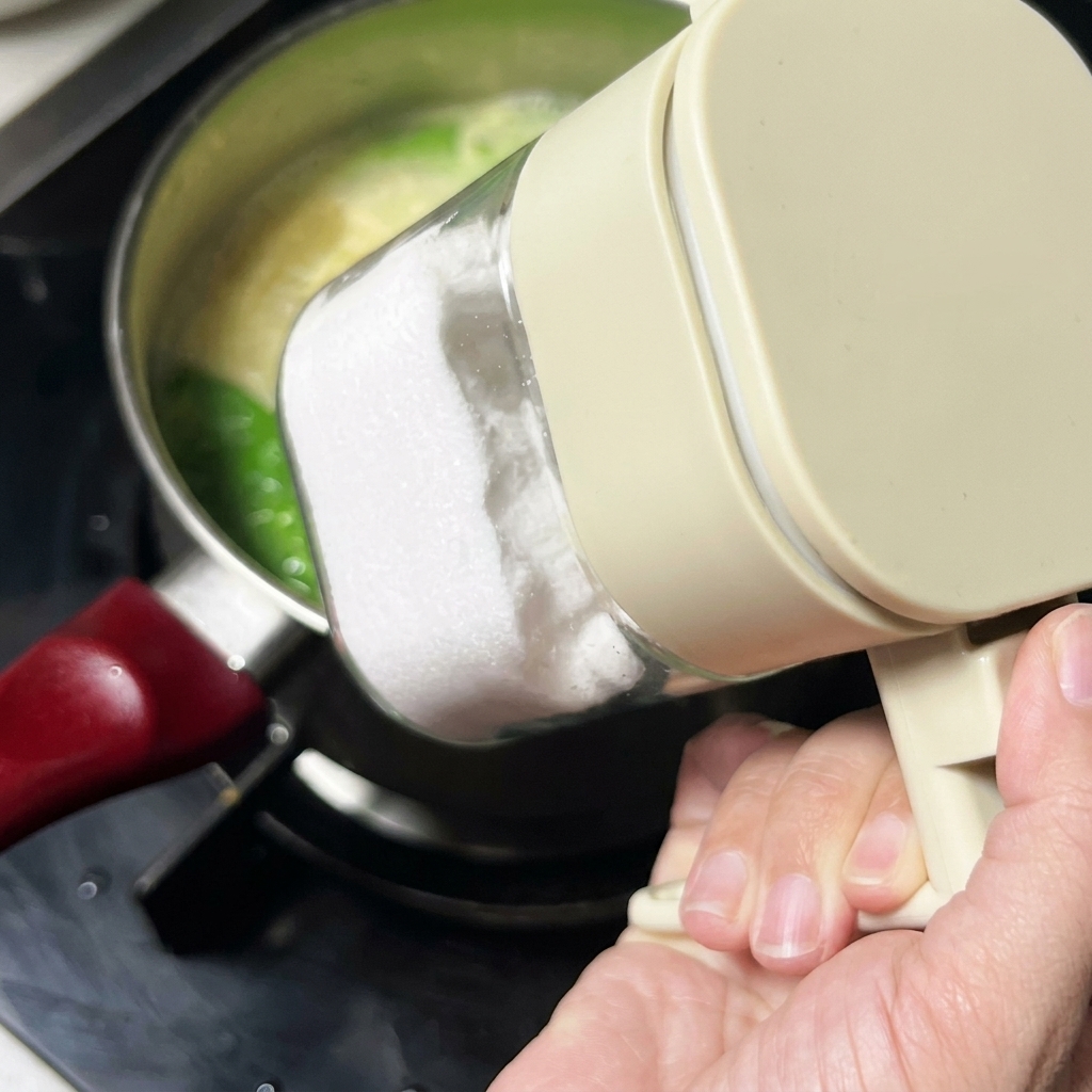 Salt being added to the soup from a clear plastic seasoning container.
