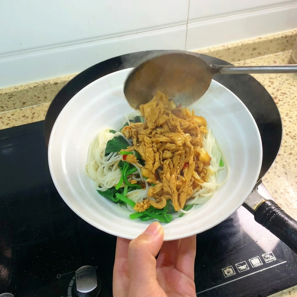 A ladle pouring a generous portion of braised shredded chicken and sauce over a bowl containing noodles and leafy greens.