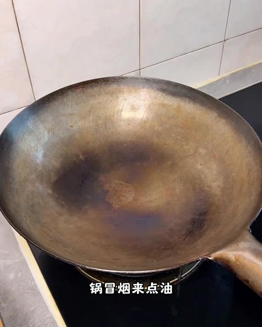 A hot, seasoned wok on a stovetop with wisps of smoke visible.