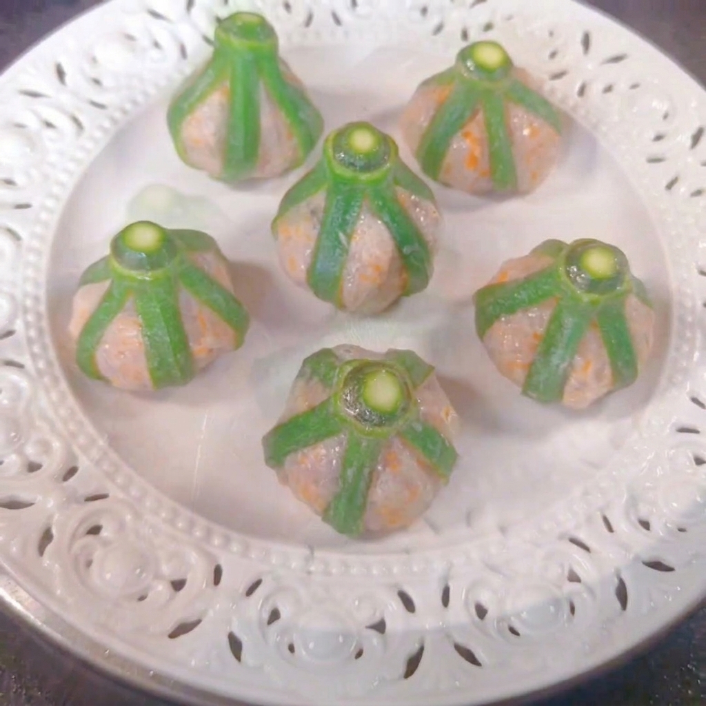 Six okra shrimp bites arranged on a white plate inside a steamer.