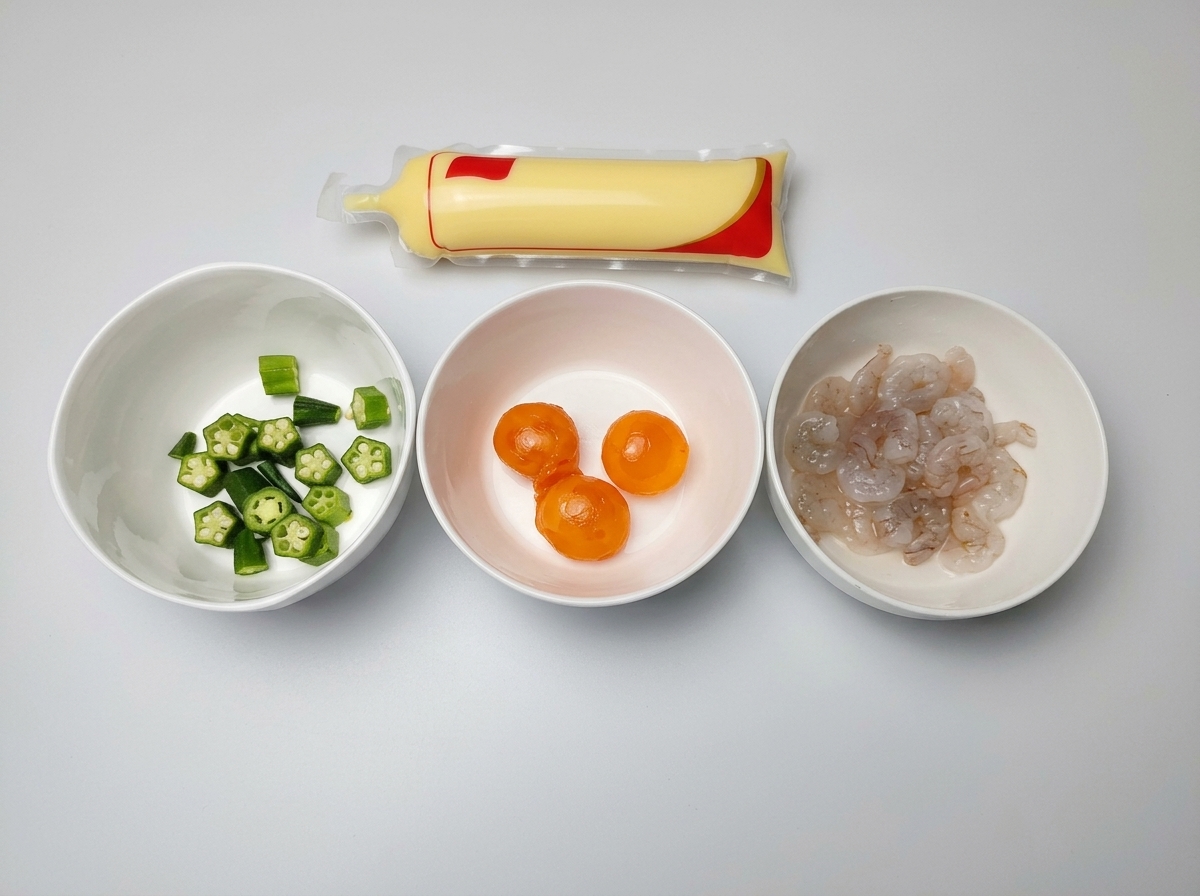 Three white bowls containing chopped okra, salted egg yolks, and raw shrimp, next to a packaged tube of egg tofu.