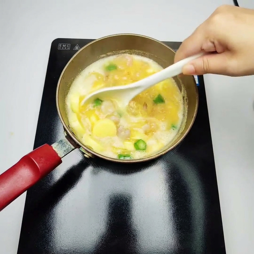 A white ladle gently stirring a simmering yellow soup filled with cooked shrimp, green okra chunks, and sliced egg tofu.