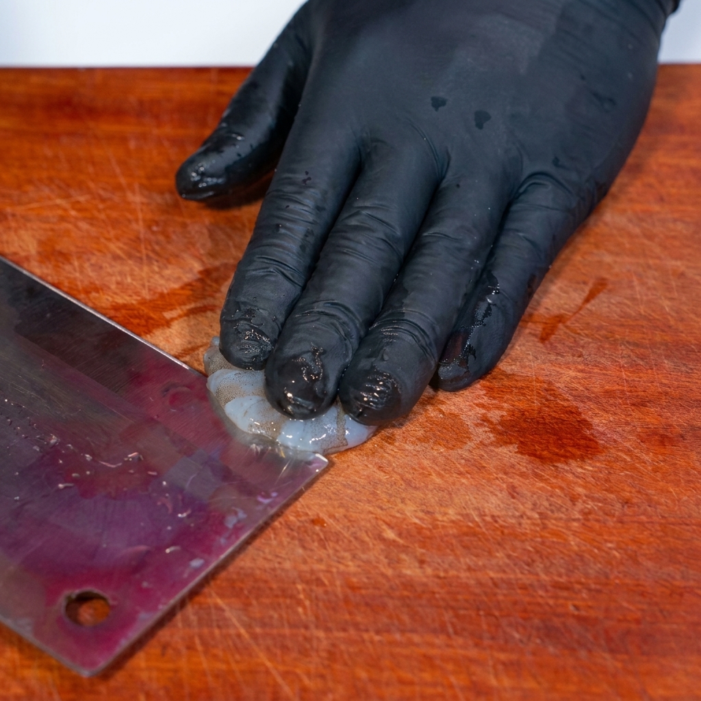 Making a shallow cut on the back of a shrimp with a knife to remove the vein.