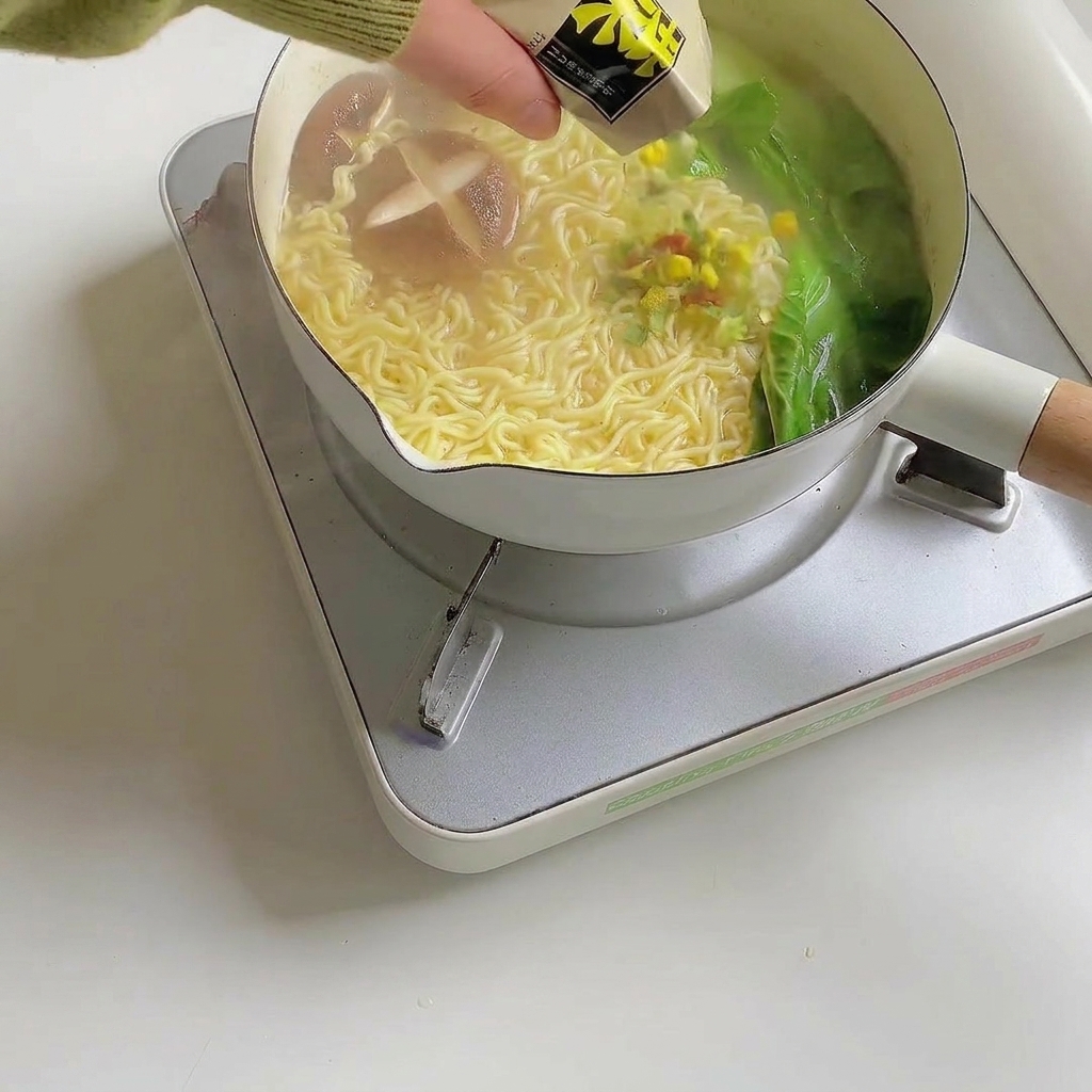 Ramen garnishes being sprinkled over the finished noodle soup.