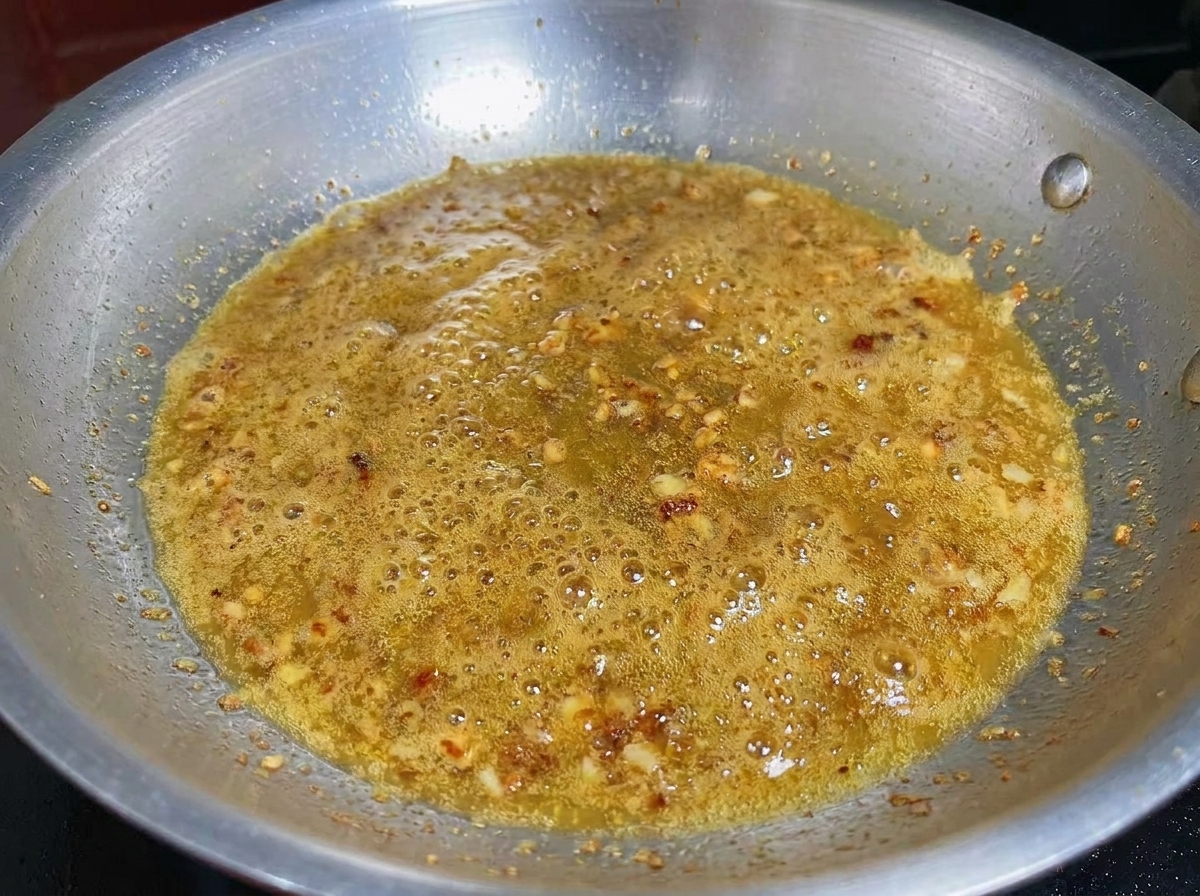 Minced garlic and shrimp cooking together in an infused olive oil base.
