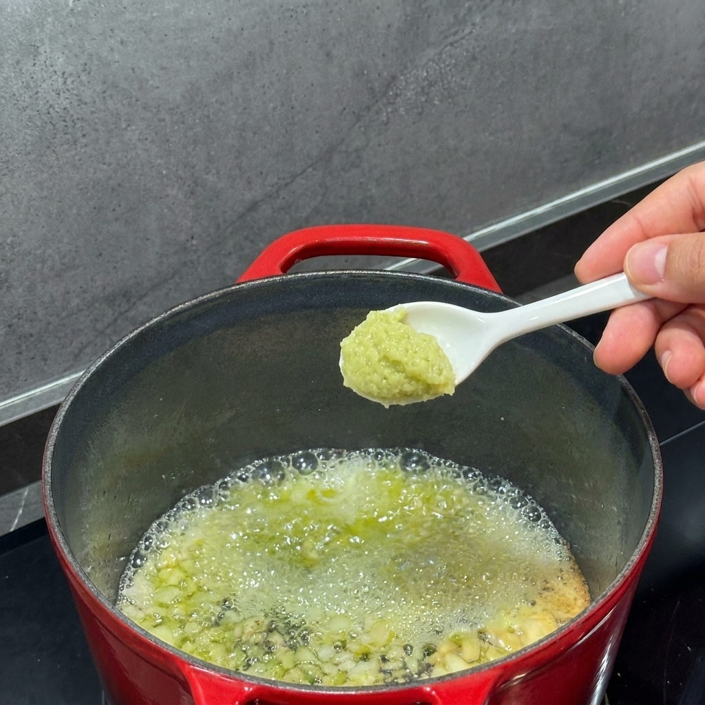 Flour being whisked into melted butter in a pot.