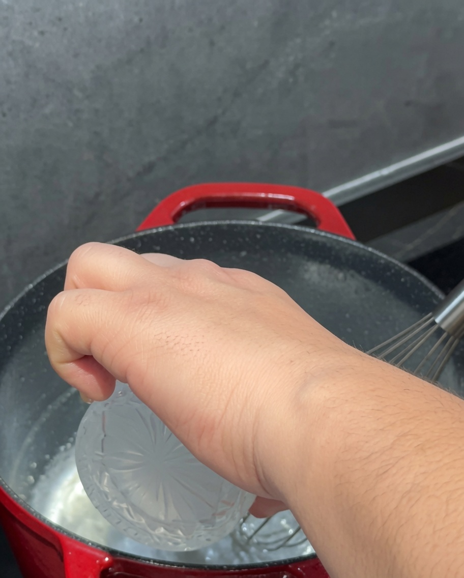 Milk being poured into the pot and whisked with the roux.