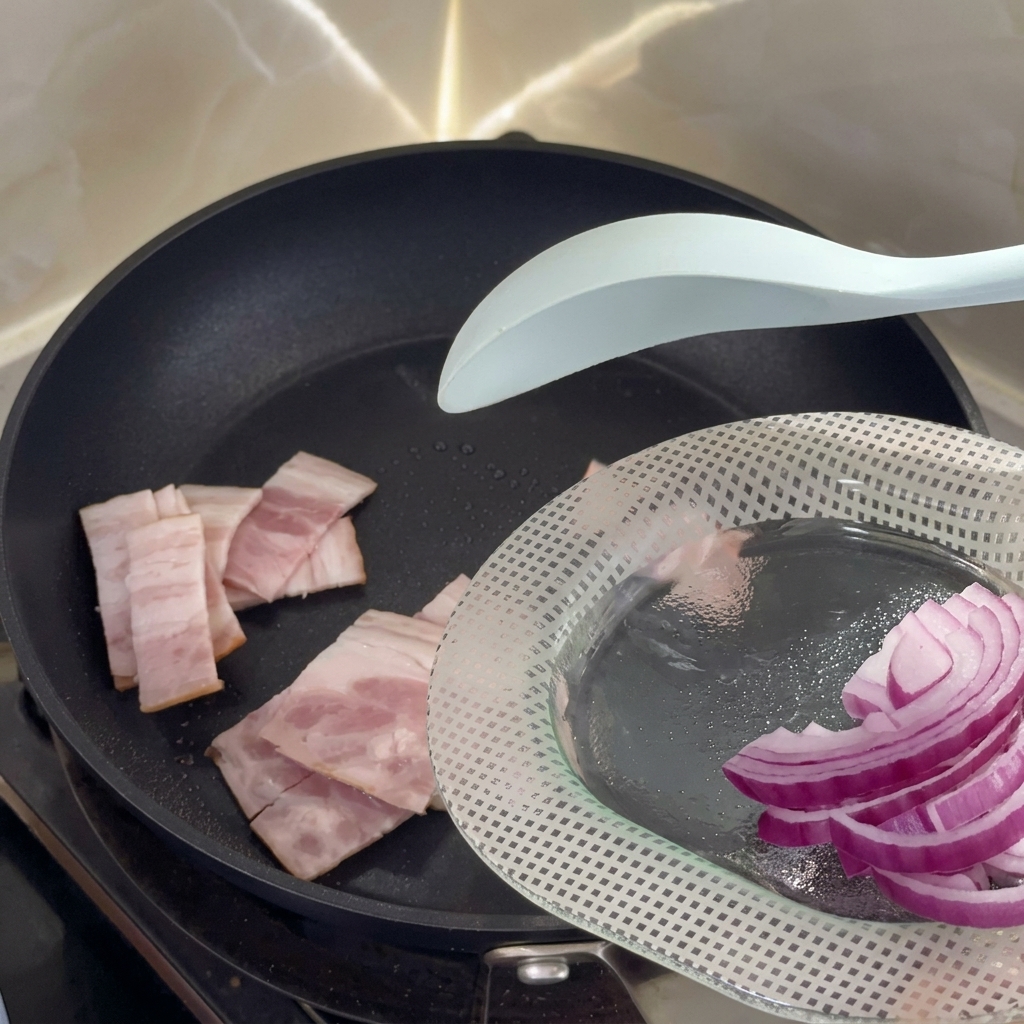 Raw bacon pieces starting to sizzle in a hot non-stick pan.