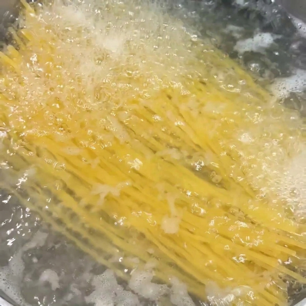 Spaghetti noodles submerged and cooking in a pot of vigorously boiling water.