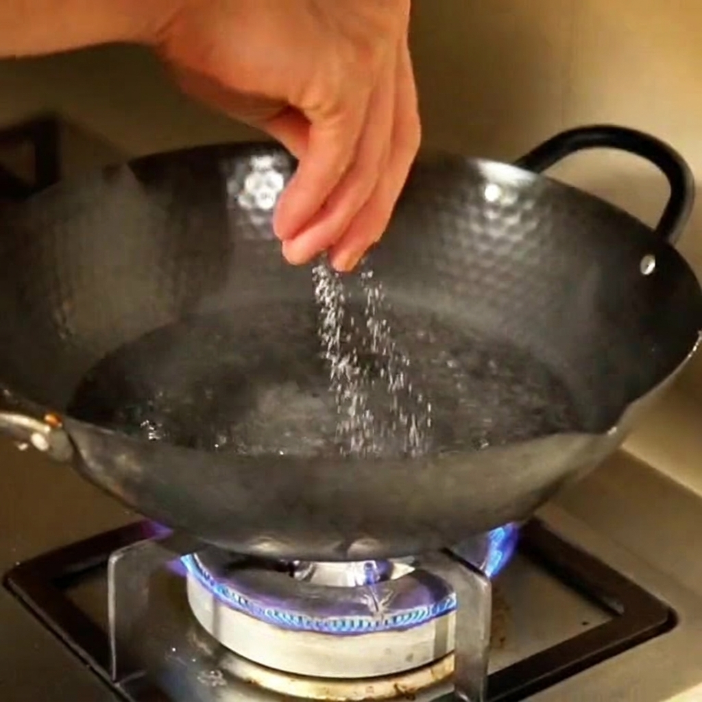 A hand sprinkling salt into a large pot of boiling water on the stovetop.