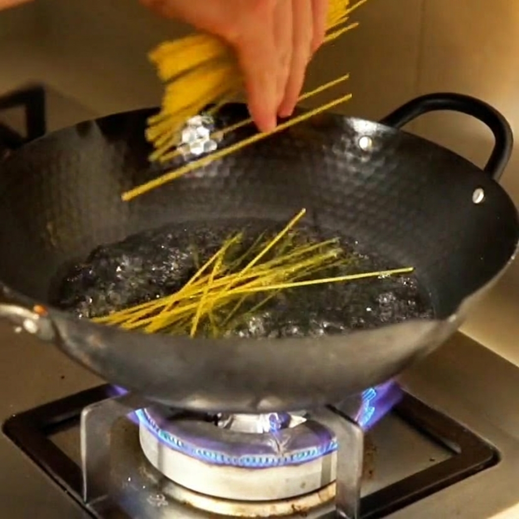 Corn noodles being submerged into a pot of boiling water.