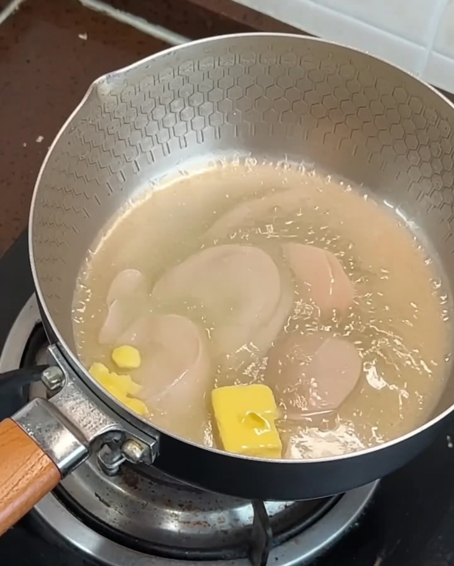 Slices of bacon and garlic frying in a pan with melting butter.
