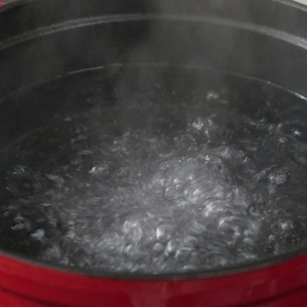Pasta submerged in a large pot of boiling, bubbling water.