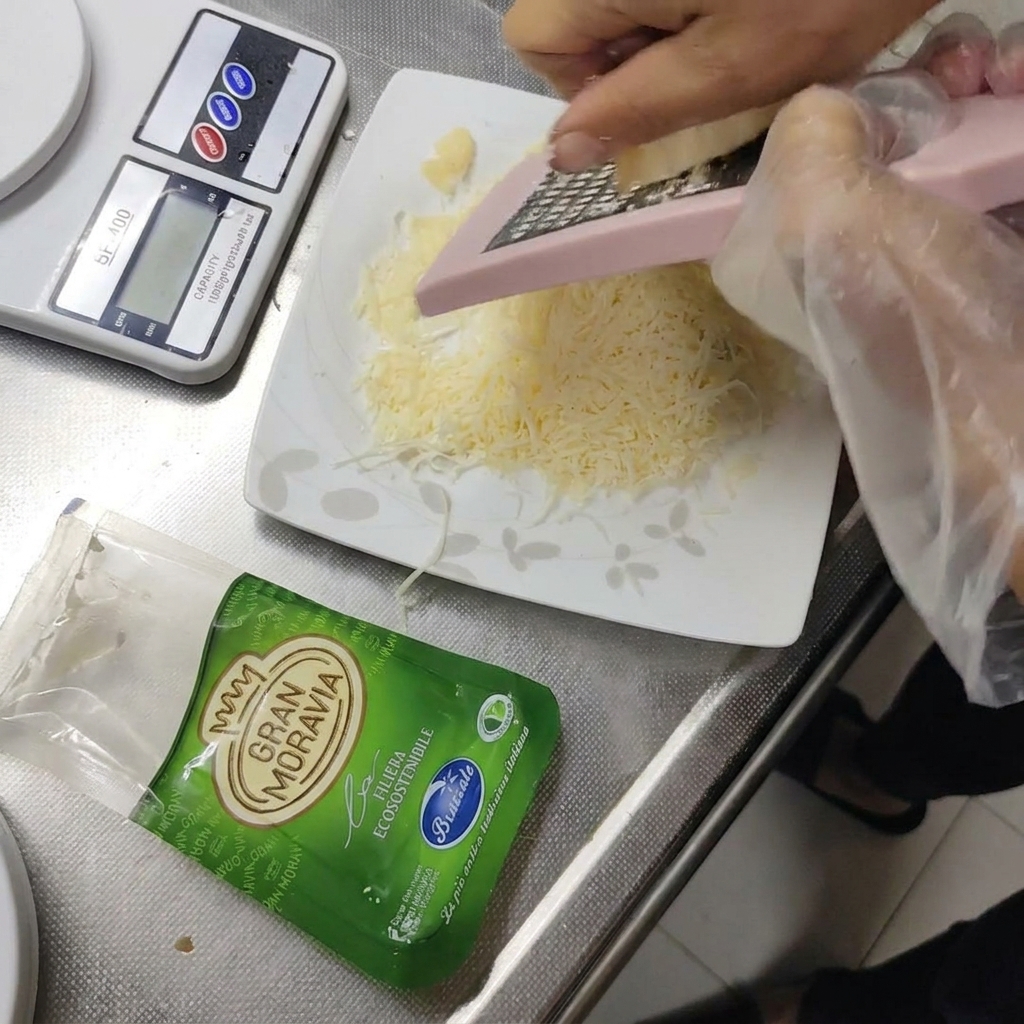 Gran Moravia hard cheese being grated onto a small plate.