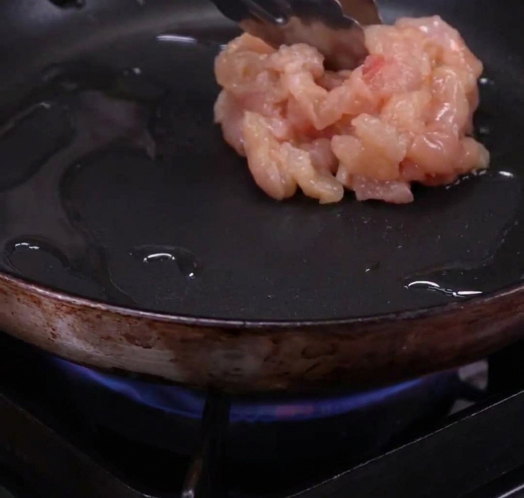 Chicken strips browning in a hot skillet with olive oil.