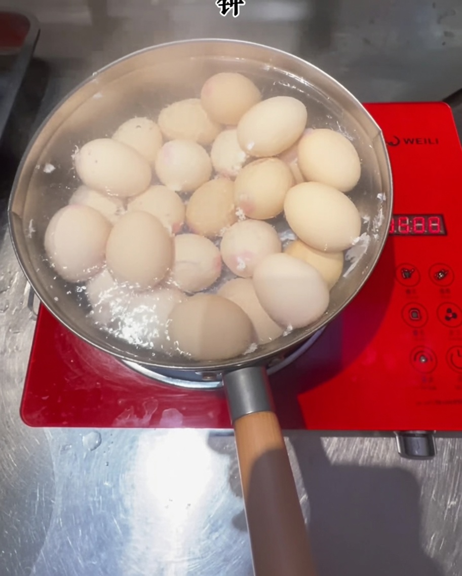 Eggs cooking in a pot of boiling water on an induction cooktop.