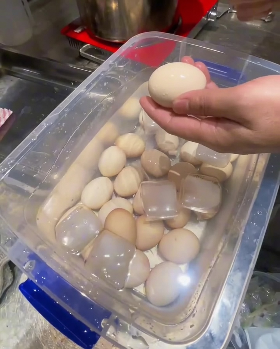 Removing eggshells from cooled hard-boiled eggs using a metal spoon.