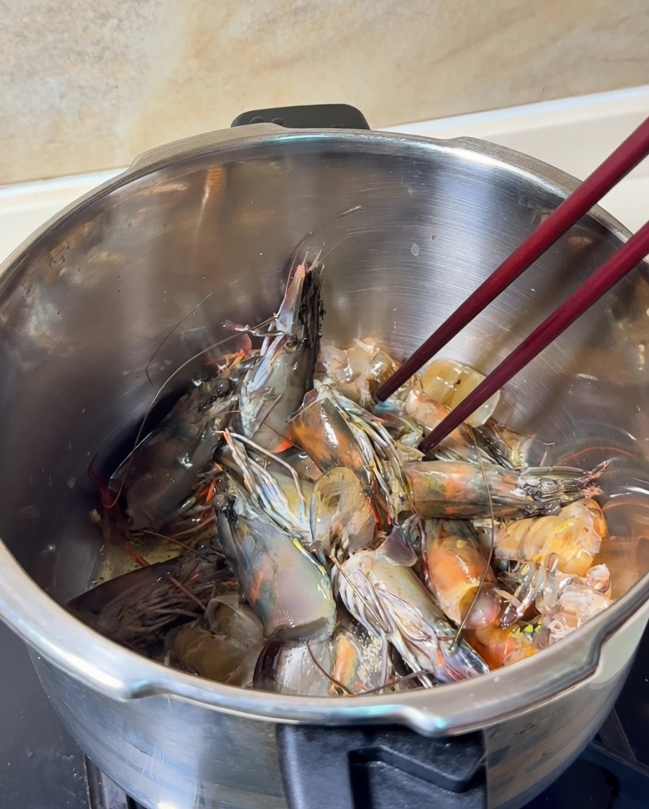 Shrimp heads and shells being stir-fried in a pot, turning a bright orange color.