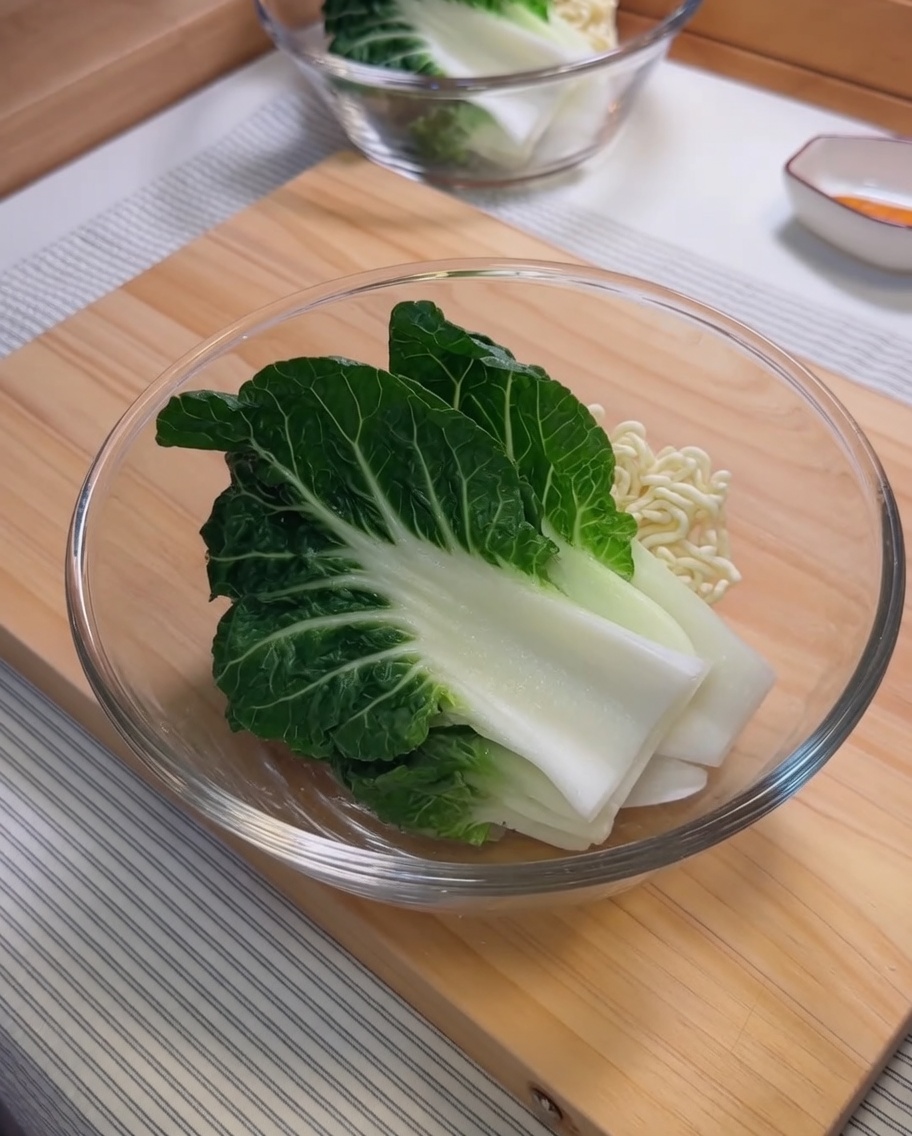 Ingredients for the sesame sauce, including sesame paste and chili oil, being mixed in a glass bowl.