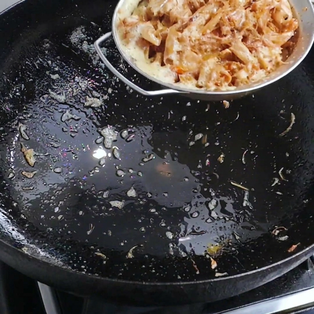 Hot water being poured into a wok containing shrimp shells to create a flavorful broth.