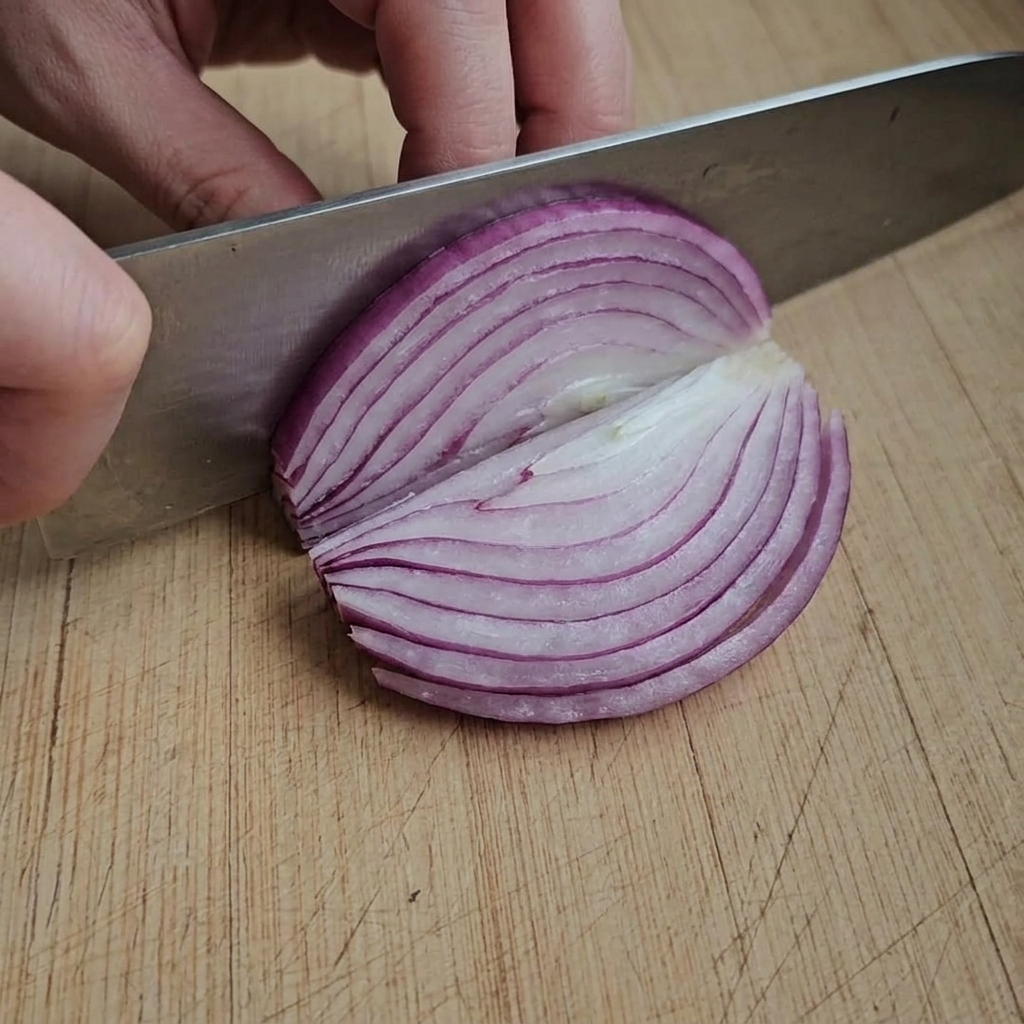 Thinly sliced red onion pieces arranged on a wooden cutting board.