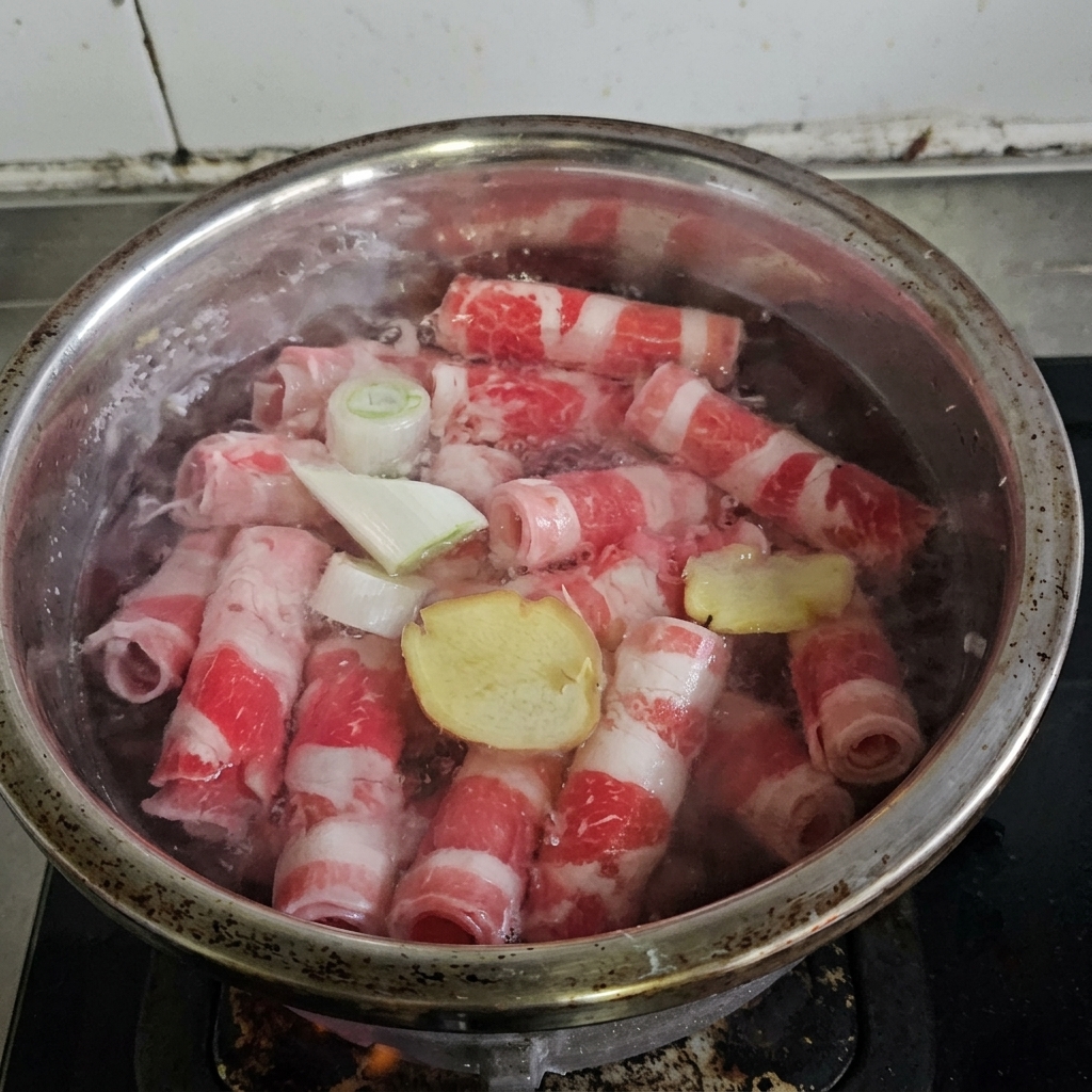 Beef rolls boiling in a pot with aromatics and cooking wine.