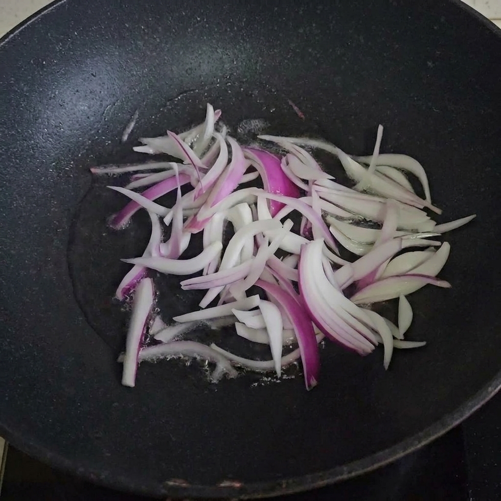 Onion slices cooking in a hot oiled pan.