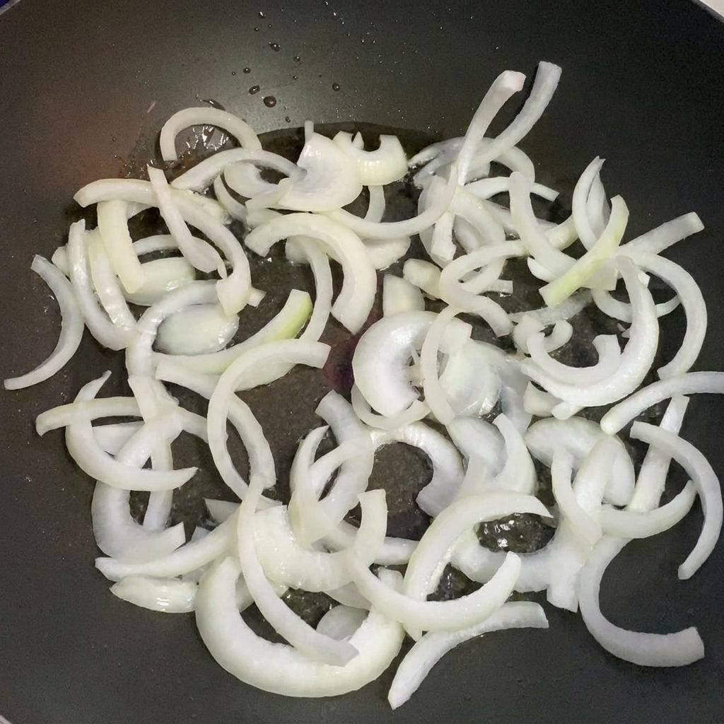 Onion slices sautéing in a pan with hot oil.