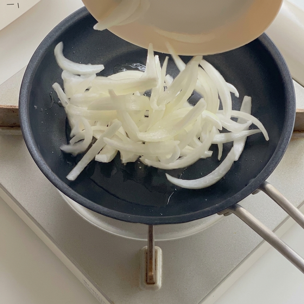 Onions softening in a pan with hot oil.
