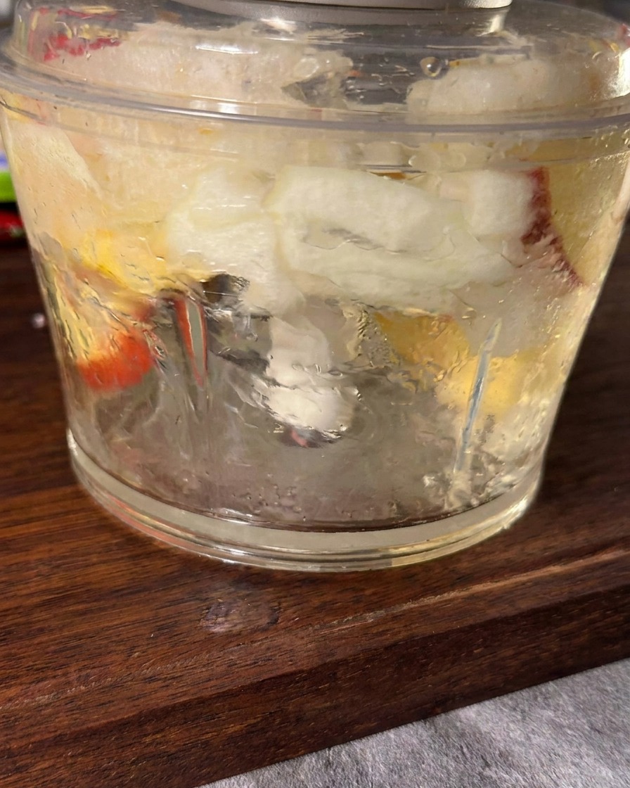 Smooth blended mixture of apple, onion, garlic, and ginger inside a blender jar.