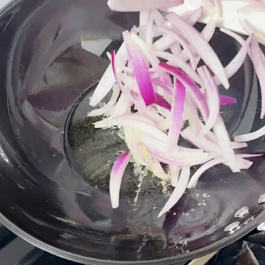 Slices of red onion being stir-fried in a wok.