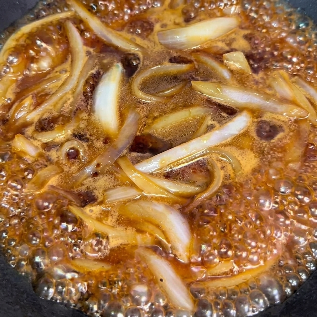 Blanched beef rolls added to the wok with onions and sauce.