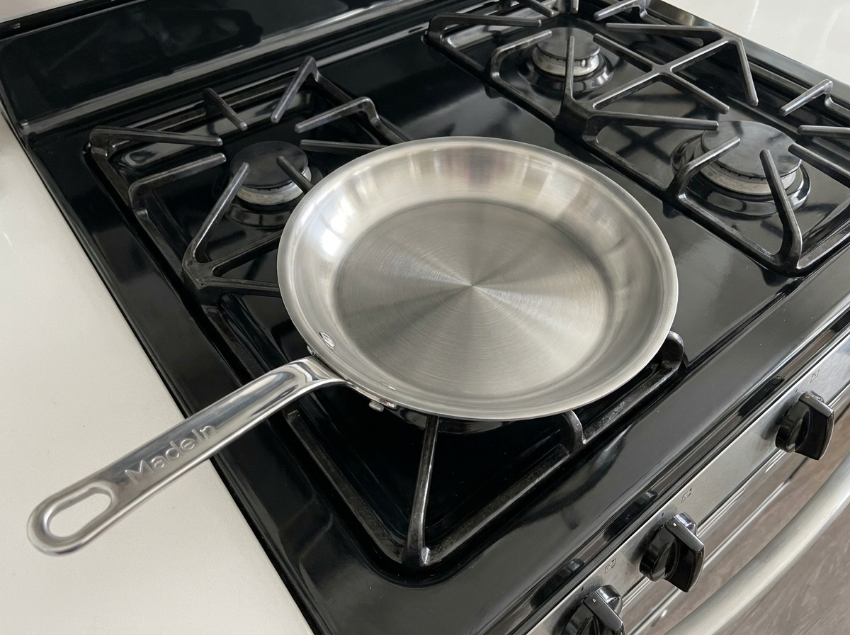 A mesh skimmer lifting golden, crispy batter flakes from the surface of the hot frying oil.