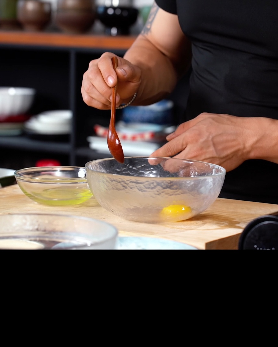 An egg yolk and cold water in a glass bowl, ready to be whisked with tempura flour.