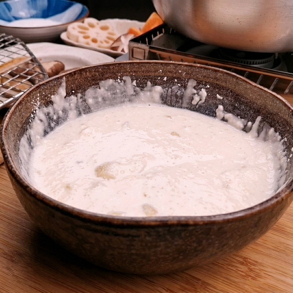Ice water being poured into a bowl of tempura flour to create a smooth batter.