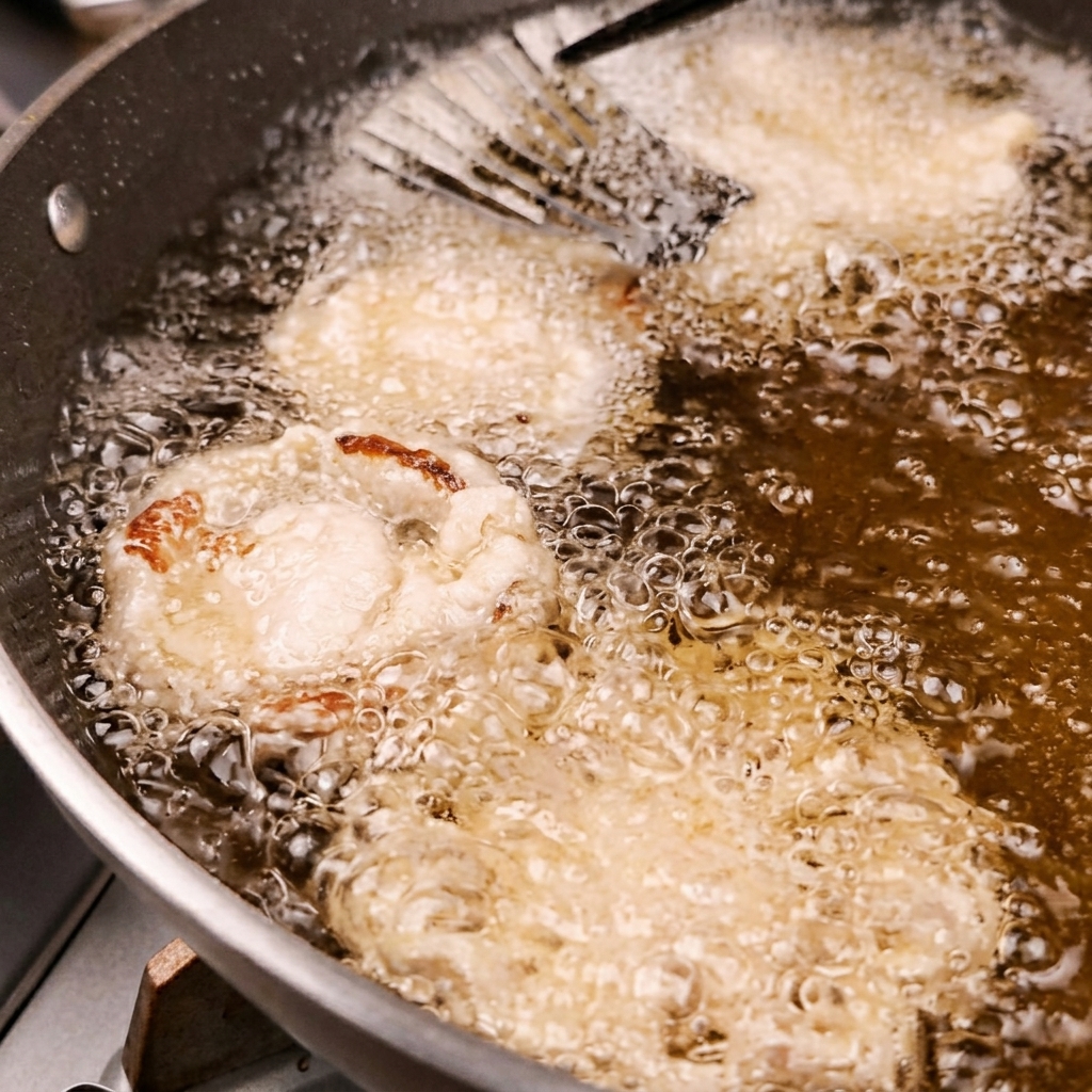 Assorted battered vegetables bubbling and frying in a pan of hot oil.