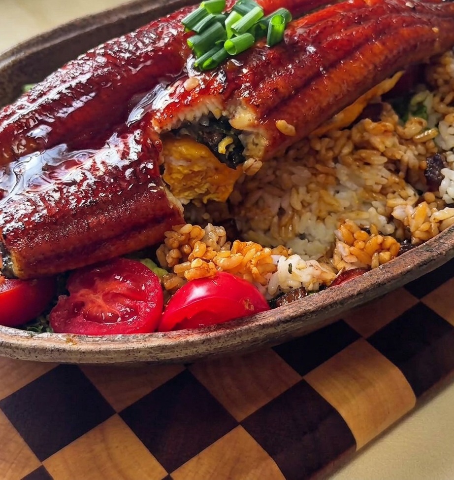 A close-up view of teriyaki onion sauce being spooned over a mound of white rice on a plate.