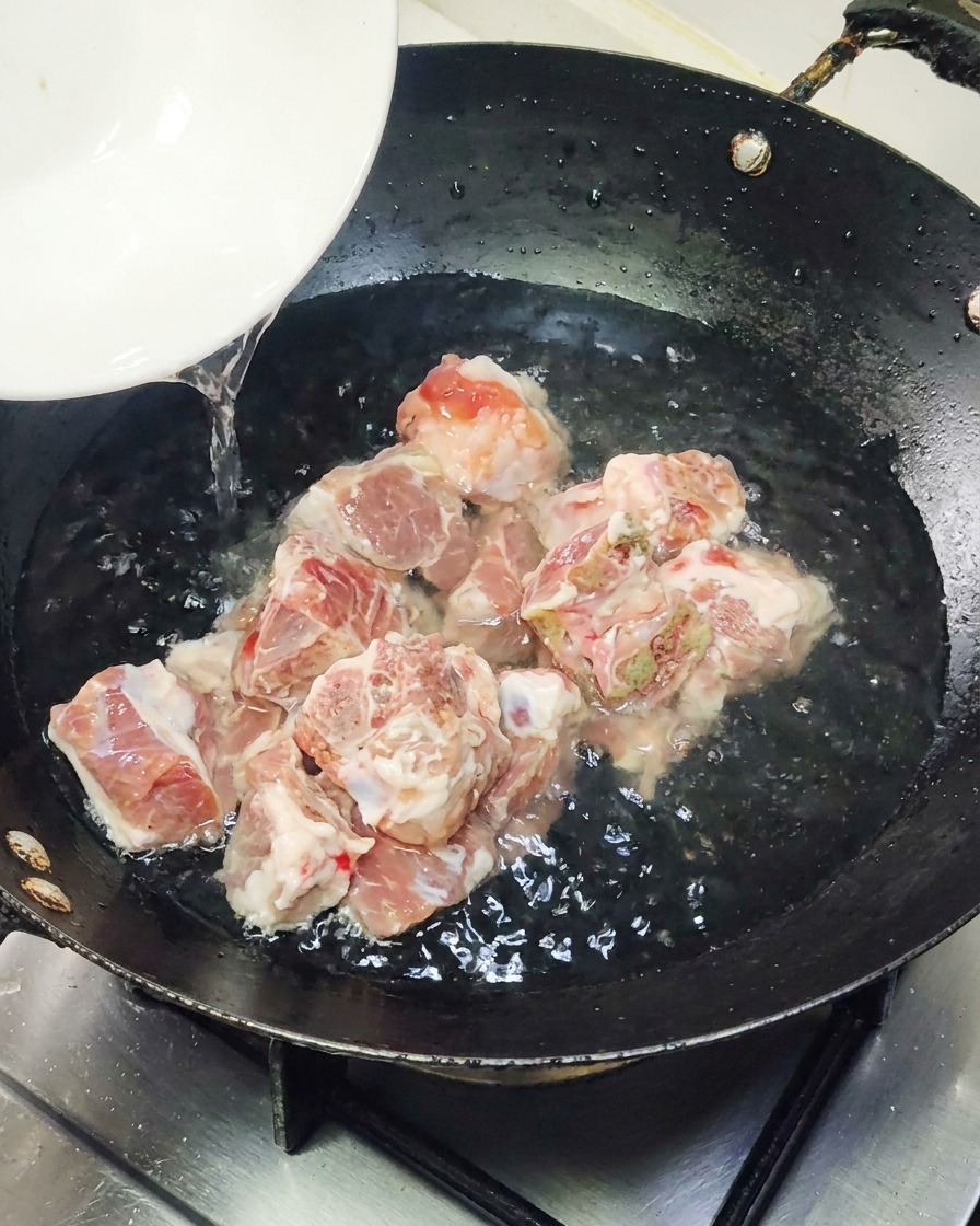 A piece of pre-packaged grilled eel being placed into a hot frying pan.