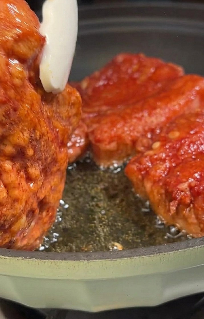 Pork belly strips frying in a pan, turning golden-brown.