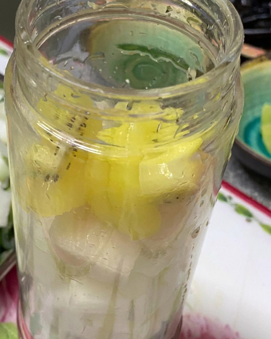 Onions, garlic, kiwi, and pear chunks inside a blender canister ready to be puréed.