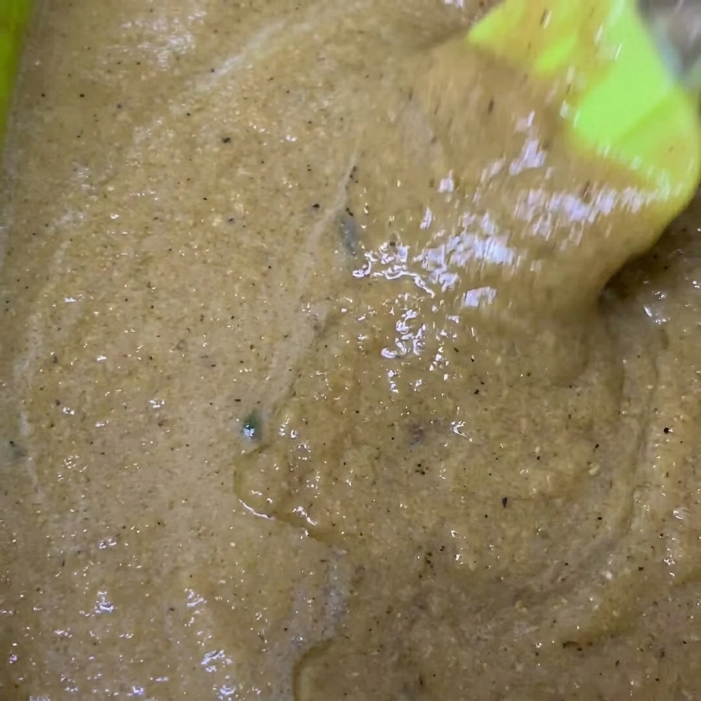 A green mixing bowl containing the blended marinade with soy sauce and black pepper added.